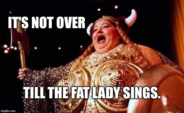 a large lady wearing a metal hat with horns on either side mouth open as if singing captioned It's not over till the fat lady sings